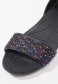 Sandale noire à enfiler avec semelle texturée et bride décorée de petites perles colorées en orange, bleu, violet, rose et argenté.