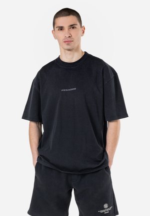Zwart oversized t-shirt met korte mouwen, voorzien van een subtiele "PEGADOR" logo in donkergrijs, gemaakt van katoen met een zachte textuur.