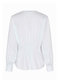Blusa bianca con scollatura rotonda, maniche lunghe a sbuffo e arricciatura elastica sul retro. Realizzata in un tessuto leggero e liscio.