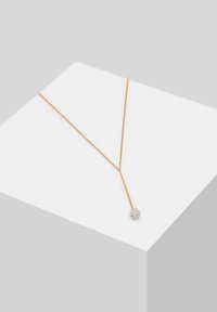 Guld kæde halskæde med en Y-formet design og en rund, funklerende vedhæng i enden. Glat tekstur, minimalisisk udseende.