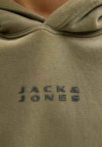 Felpa verde oliva con una texture morbida. Presenta un grande logo in rilievo nero "JACK & JONES" sul davanti.