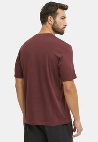 T-shirt corto marrone, con maniche corte e scollo rotondo, realizzato in cotone morbido. Design semplice con vestibilità comoda. Dettaglio di cucitura visibile sul retro.