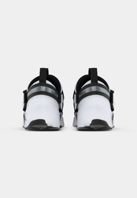 Ζευγάρι λευκών και μαύρων αθλητικών παπουτσιών από πίσω σε άσπρο φόντο.