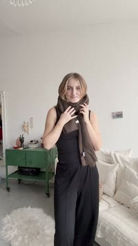 Bufanda marrón enrollada alrededor del cuello, hecha de material suave, con un diseño simple y sin patrones visibles. Adecuada para uso casual.