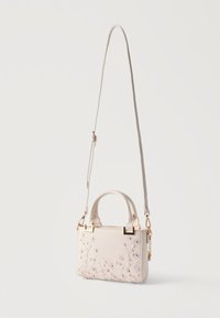 Petit sac à main beige avec deux poignées et une longue bandoulière ajustable, orné d'une broderie florale rose et blanche sur le devant.