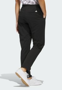 Svarta joggerbyxor i lättviktstyg med avsmalnande passform, elastisk midja och två bakfickor med subtil logotypdetalj.