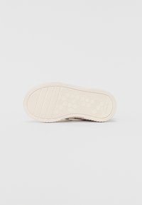 Weiße Sneaker-Sohle mit einem strukturierten, Wabenmuster, das Rillen und eine leichte Krümmung aufweist; seitlich mit "Clarks" markiert.