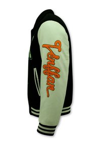 Zwart en crèmekleurig varsityjack met een zachte textuur, met een oranje geborduurd "Tensfan" op de crèmekleurige mouw en gestreepte boorden.