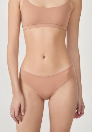 Beiges nahtloses Bralette und passendes Bikini-Unterwäsche-Set aus einem glatten, dehnbaren Material. Verfügt über ein minimalistisches Design mit dünnen Trägern.