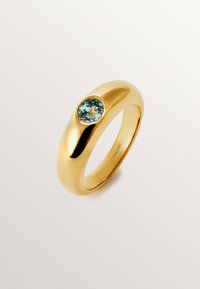 Anillo de oro con una banda suave y redondeada que presenta una gema azul cielo engastada en un bisel. Acabado pulido con una superficie reflectante.