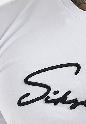 Biała koszulka z krótkim rękawem, z wyraźnym czarnym haftowanym logo w stylu kursywy na przodzie, gładką tkaniną i klasycznym okrągłym dekoltem.