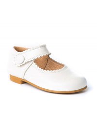Zapato de cuero blanco con punta redonda y bordes festoneados. Cuenta con una sola correa ajustable estilo Mary Jane y una suela de goma marrón.
