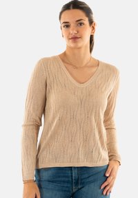 Maglione beige lavorato a maglia con scollatura a V, maniche lunghe e motivi a onda testurizzati. Il tessuto presenta una leggera lucentezza e un orlo a coste.