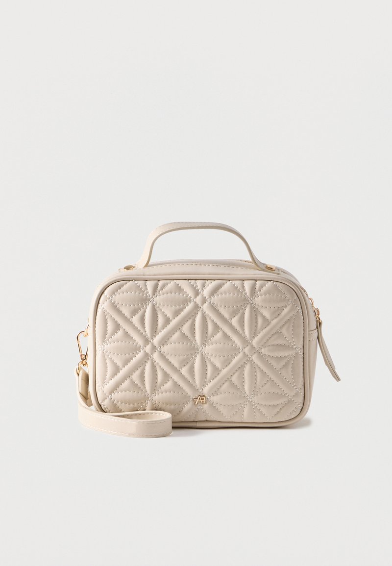 Μπεζ καπιτονέ ορθογώνια τσάντα με χειρολαβή στο πάνω μέρος, αποσπώμενο ιμάντα ώμου, χρυσστό φερμουάρ και μικρό χρυσό λογότυπο στο κέντρο του μπροστινού μέρους.