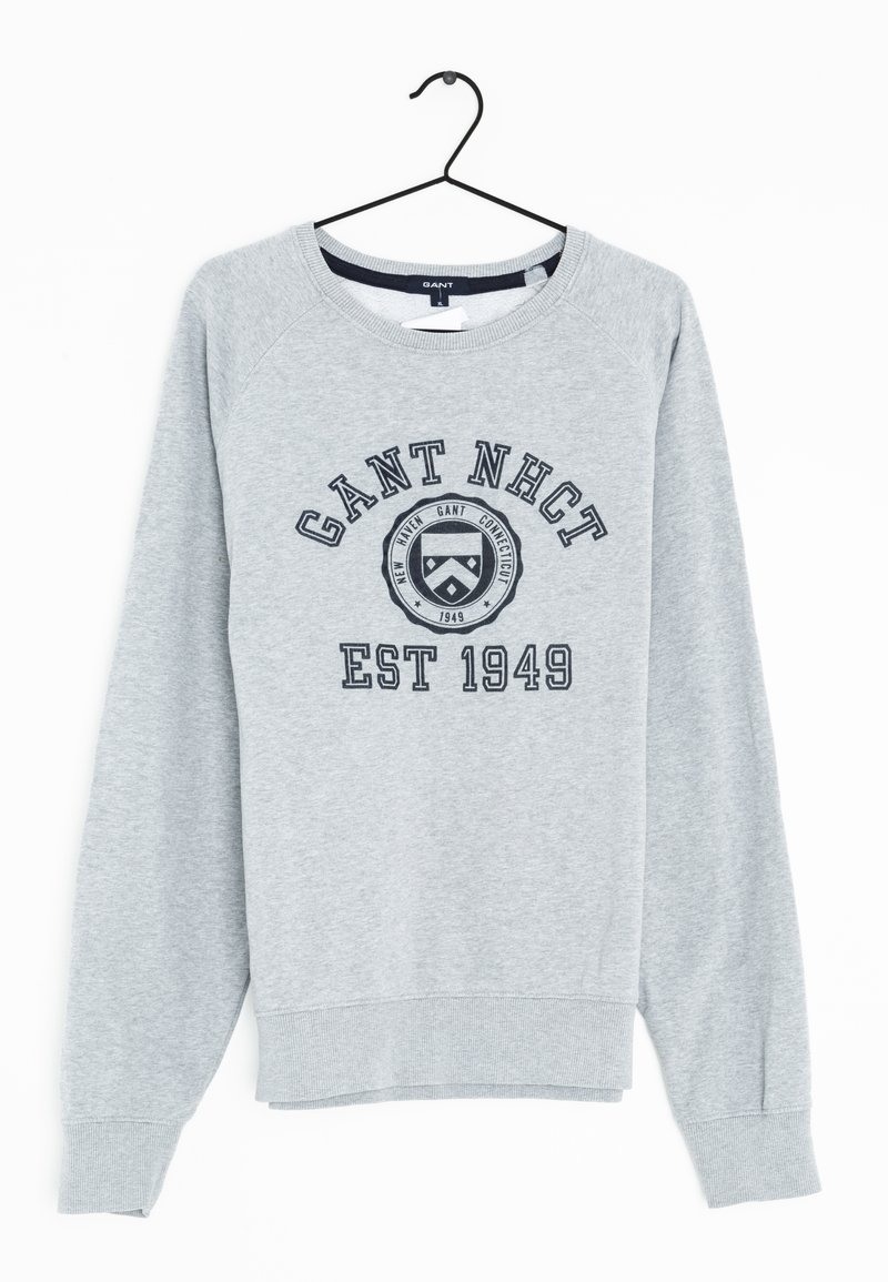 Sweatshirt gris avec un col rond, des manches raglan et des poignets côtelés. Présente un texte noir et un design de logo circulaire à l'avant.
