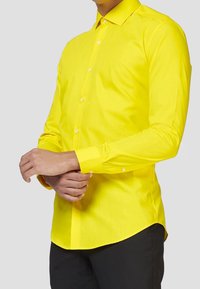 Camisa amarilla de manga larga hecha de una tela suave, con cuello abotonado y puños con un solo botón, y con un corte ajustado.