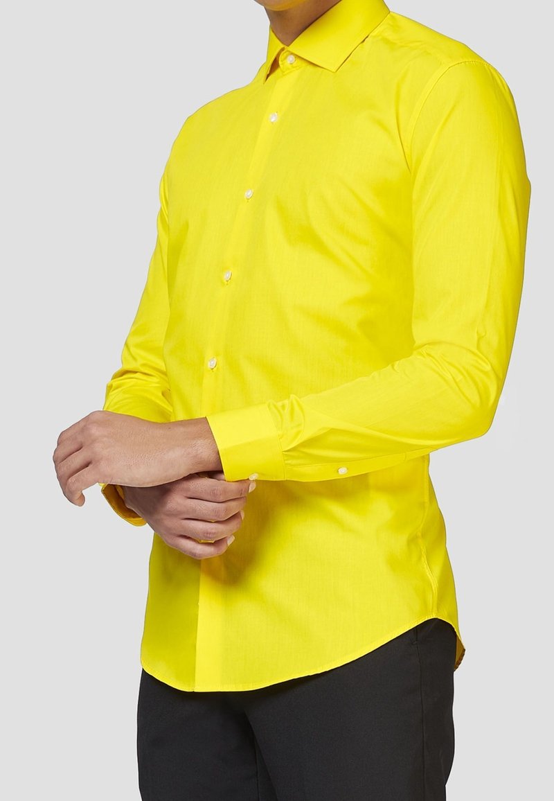 Camisa amarilla de manga larga hecha de una tela suave, con cuello abotonado y puños con un solo botón, y con un corte ajustado.