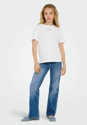 Hvid t-shirt med korte ærmer, hvor "CHERRY" er trykt i blåt, parret med lyseblå flagrende jeans og blå slip-on sko. Glat bomuldsstruktur.