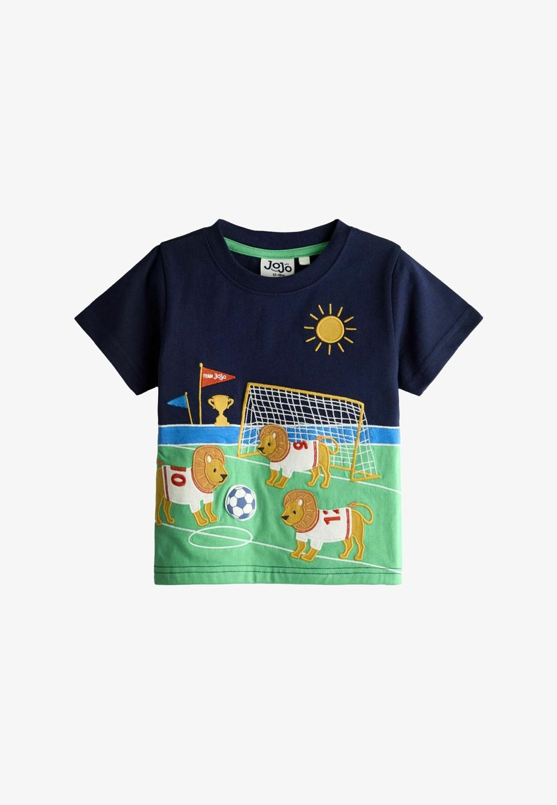 Chemise pour enfants bleu marine et verte avec des lions portant des maillots de football jouant avec un ballon sur un terrain, avec un but, un trophée, des drapeaux et le soleil.