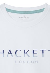 Bílý bavlněný tričko s kulatým výstřihem, s modrou gradientní logem 'HACKETT LONDON' na hrudi a světlou tyrkysovou límečkem.