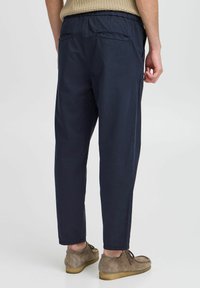 Navy lightweight pants with an elastic waistband; features two back pockets and tapered legs. Soft fabric with a smooth texture.