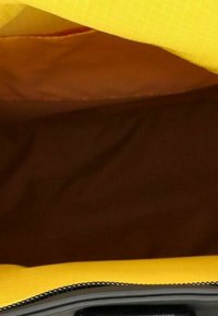 Interno di una borsa gialla con una morbida fodera marrone. La cerniera è nera, in contrasto con il materiale esterno, che presenta una trama a griglia.