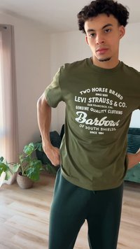 Olivengroen T-shirt met witte tekstgrafieken, voorzien van een ronde hals en korte mouwen, gecombineerd met donkergroene broek.