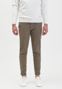 Bruine geruite broek met een slim fit, gemaakt van een gestructureerde stof. Gecombineerd met witte sneakers en een eenvoudige witte trui.
