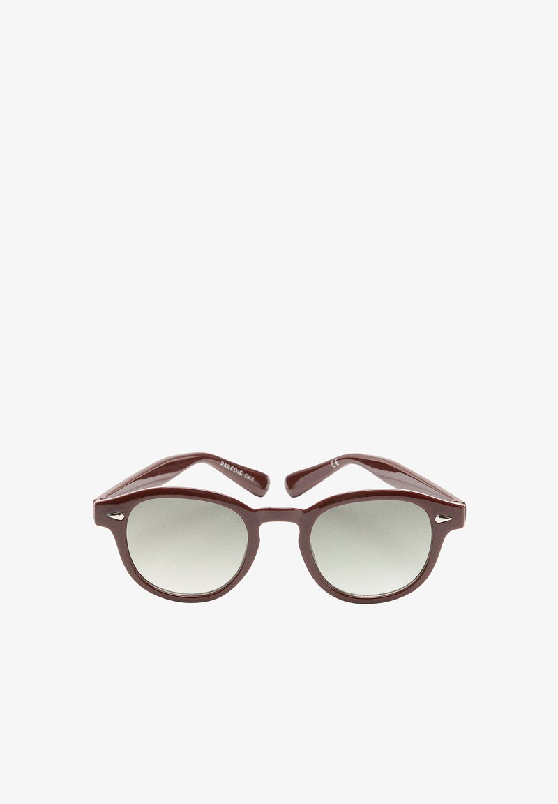 Brązowe plastikowe okulary przeciwsłoneczne z gradientowymi szarymi szkłami. Kształt kocich oczu z cienkimi zausznikami i małym akcentem logo na oprawce.