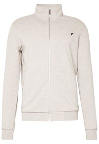 Chaqueta de color beige claro con cremallera completa, cuello alto, mangas largas, puños y dobladillo acanalados, y un pequeño logo de un pájaro negro en el pecho.