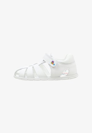 Sandalia blanca para niños con talón cerrado, puntera abierta, correa ajustable con botón de colores y suela flexible.