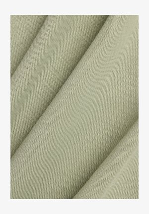 Tessuto verde chiaro con motivo a coste, che mostra un materiale morbido e lavorato a maglia drappeggiato in pieghe.