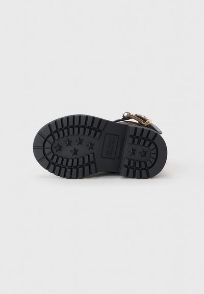 Black shoe sole with a tread pattern featuring stars. The sole includes embossed branding and a textured, durable design.