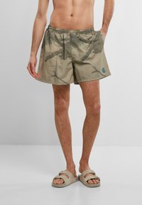 Shorts da bagno con motivo camouflage in tessuto verde oliva, dotati di una cintura elastica e tasche laterali, con un piccolo logo blu sull'orlo.