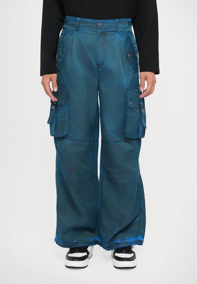 Pantalons cargo en tissu dégradé bleu, avec plusieurs poches latérales, coupe ample, ourlets effilochés et accents en métal noir.