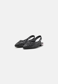 Zapatos de slingback tejidos en negro con puntera puntiaguda, que presentan un diseño con recortes y un tacón pequeño. Fabricados con material flexible para mayor comodidad.