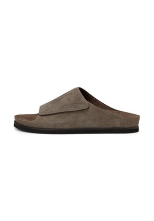Brown suede open-toe slide sandal with adjustable wide strap and black flat sole, shown in side profile on white background.