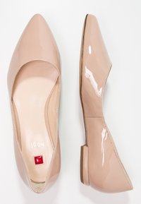 Pár béžových lakovaných balerín s špičatou špičkou, jedna z pohledu shora a druhá z bočního pohledu, na bílém pozadí.