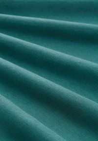 Tela de color teal con una textura suave, que presenta pliegues sutiles y una superficie uniforme. El material parece suave y maleable.