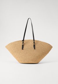 Geweven stro-tas in een waaierformat met zwarte leren handvatten en gouden accenten. De textuur is natuurlijk en lichtgewicht.