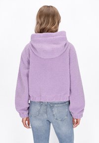 Felpa corta in lavanda realizzata in fleece testurizzato, con cappuccio, maniche lunghe e un dettagli di orlo ben tessuto.