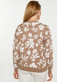 Maglione lavorato a maglia marrone chiaro con motivi floreali bianchi. Presenta polsini e orlo a costine, e un classico collo a giro.