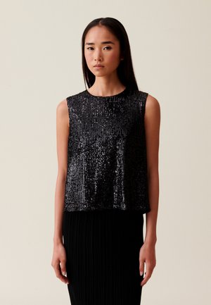 Top corto nero in paillettes con scollatura rotonda e senza maniche, caratterizzato da una texture liscia e una vestibilità ampia. Indossato con una gonna nera plissettata.