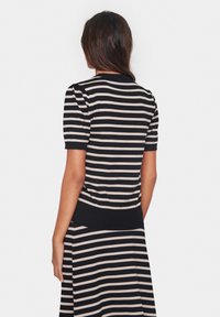 Svart och beige randig kortärmad tröja med en figurnära ribbad nederkant. Mjuk textur och puffärmar framhäver designens detaljer.