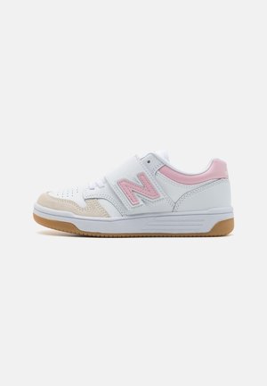 Hvid sneaker med pink logoaccent, beige tåhætter, gummisål og pink detalje på hælkanten, set fra siden på ensfarvet baggrund.