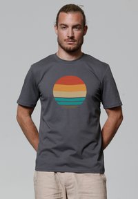 Grijze korte mouwen t-shirt met een ronde graphic met horizontale strepen in rood, oranje, geel en turquoise. Glad katoenen textuur.