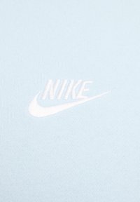T-shirt in cotone azzurro chiaro con logo Nike ricamato bianco e swoosh, che presenta una superficie liscia e texture.