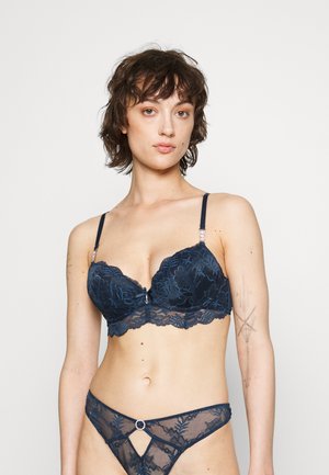 Lace bra and thong set in navy blue with floral patterns. Bra features underwire, adjustable straps, and a decorative center accent.