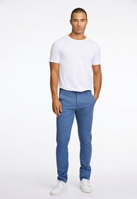 Blå chinos med slim fit, som har bältesöljor och sidofickor, kombinerat med en enfärgad vit t-shirt med rund hals och vita sneakers.