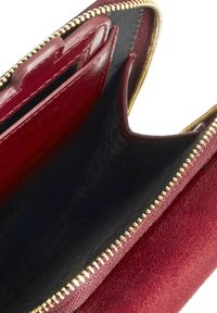 Red suede wallet interior with black lining, gold zipper, card slots, and smooth finish. Features a spacious design for organized storage.